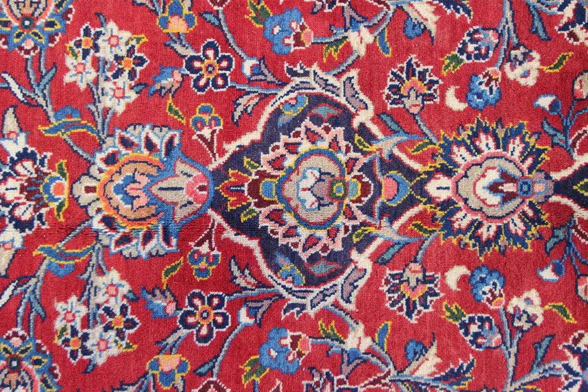 Keshan rug detail with red stripes, colorful flowers, and delicate tendrils.