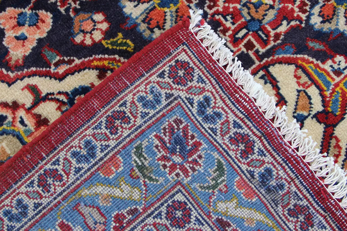 Keshan Oriental rug corner with fringe and geometric pattern in red, blue, and beige