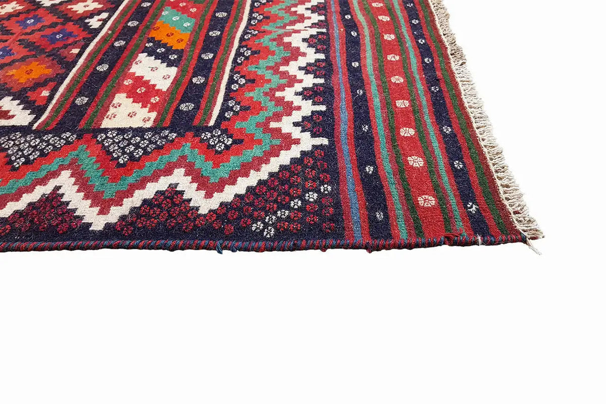 Kilim rug corner with fringes and multicolored stripes in red, blue, green, white.