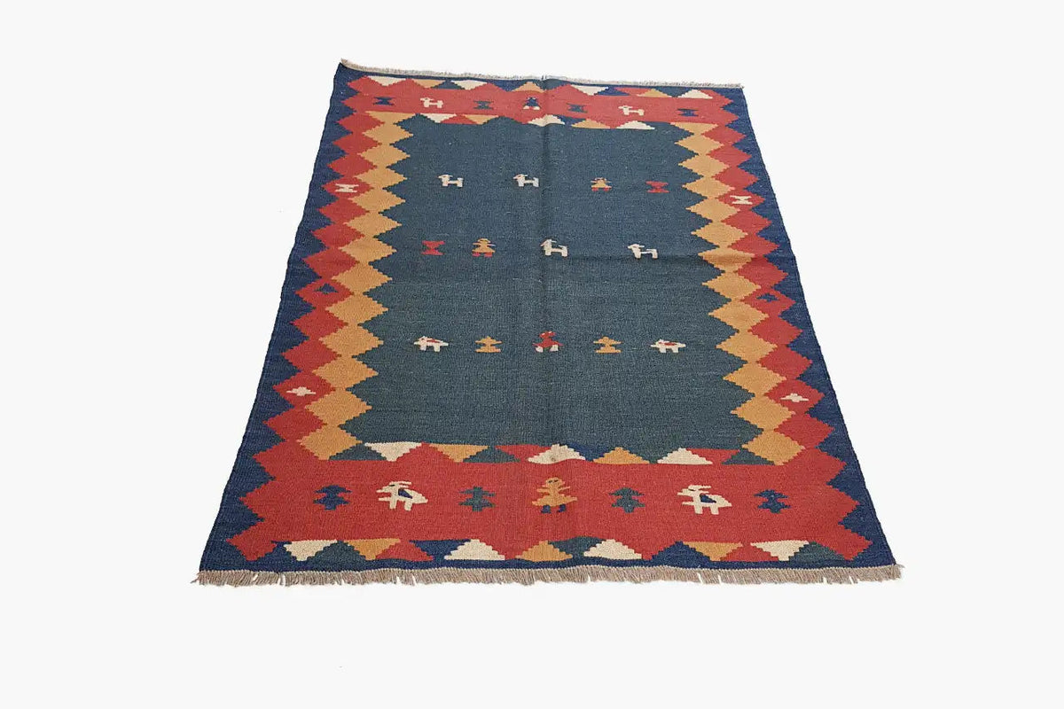 Kilim rug, front view: blue inner field with rows of symbols and multicolored diamonds along the edge