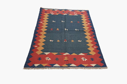 Kilim rug, front view: blue inner field with rows of symbols and multicolored diamonds along the edge