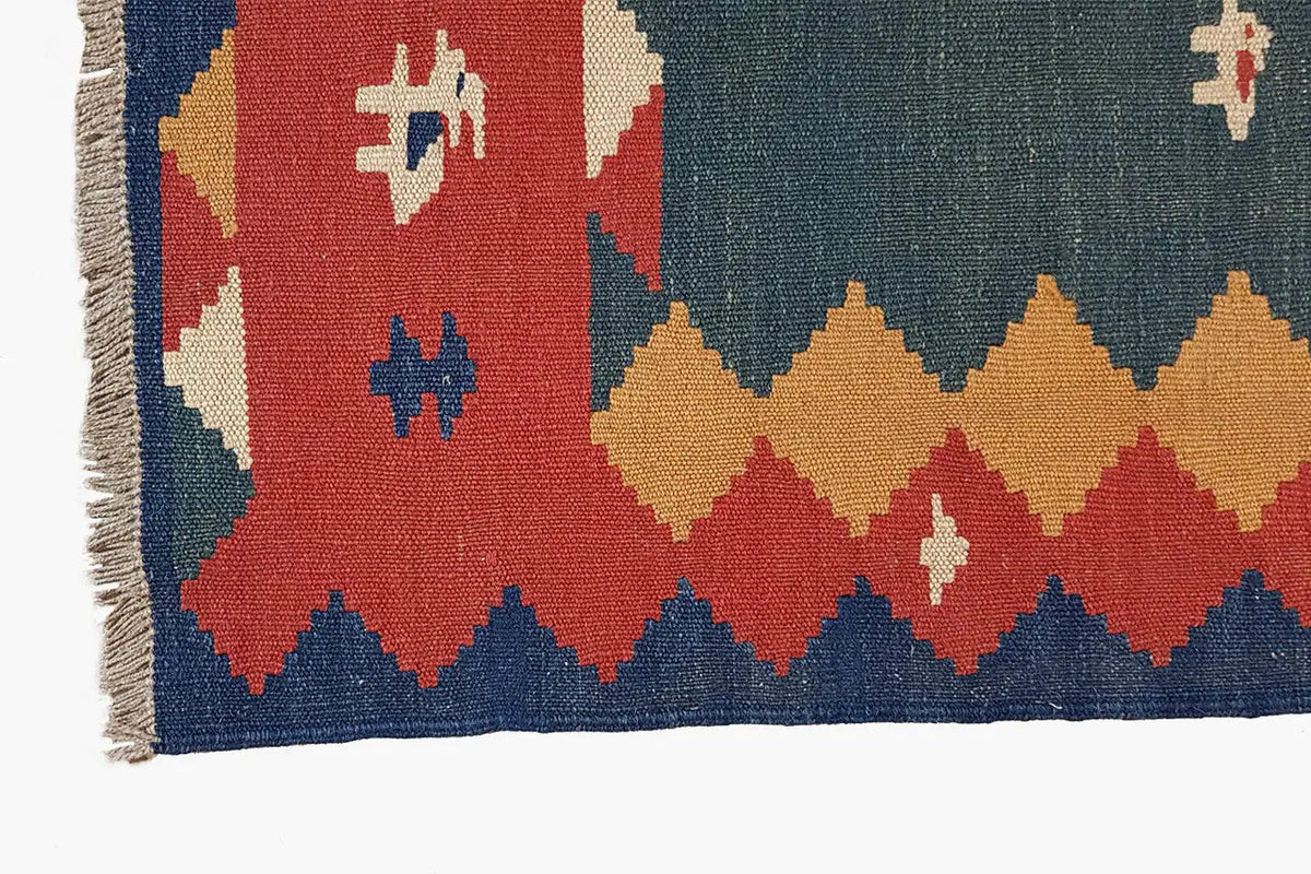 Kilim rug detail: multicolored border with geometric patterns and fringes