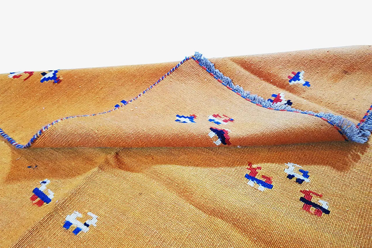 Kilim rug with a visible woven texture, colorful ornaments, and a folded section