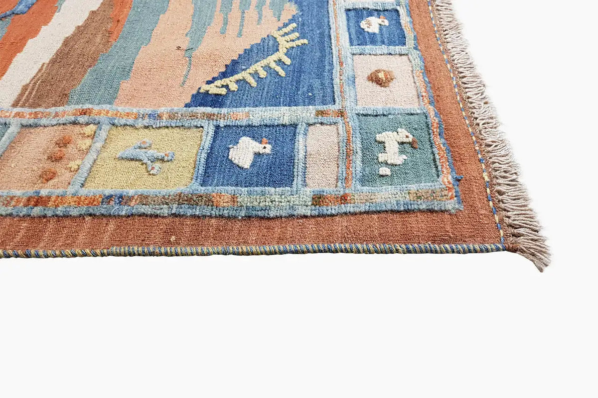 Kilim rug with a blue, beige, and orange pattern and fringes along the edge