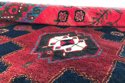 Close-up: white diamond medallion and surrounding ornaments on a red-and-blue Oriental rug.