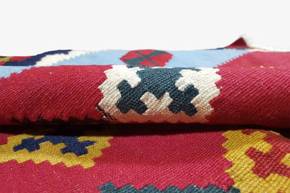 Close-up: red kilim with woven ornaments in blue, white, and yellow