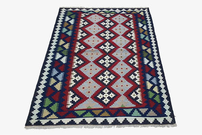 Colorful kilim rug with a geometric pattern, rectangular, with fringes along the edge.