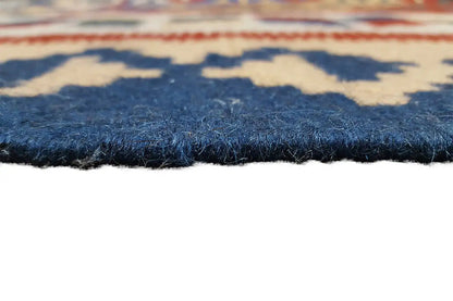 Close-up of a kilim rug: dense pile at the edge, blue fabric with ornamental stripes