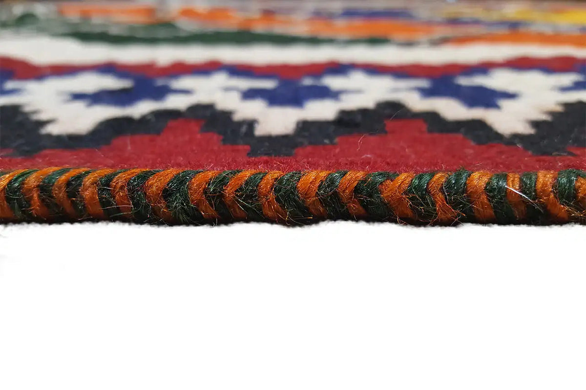 Rug edge with multicolored fringes and a woven pattern in green, blue, and orange
