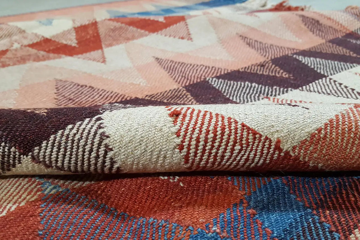 Rug with a woven zigzag pattern in rust, blue, and beige (close-up)