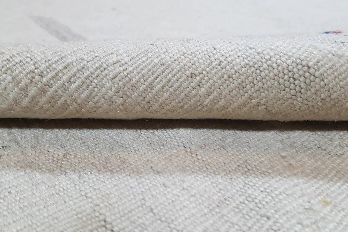Close-up of a light beige kilim rug: woven texture and edge finish