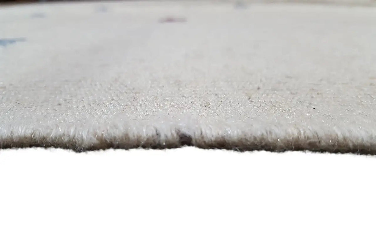 Close-up of the edge of a light beige kilim: short fringe and fine woven texture