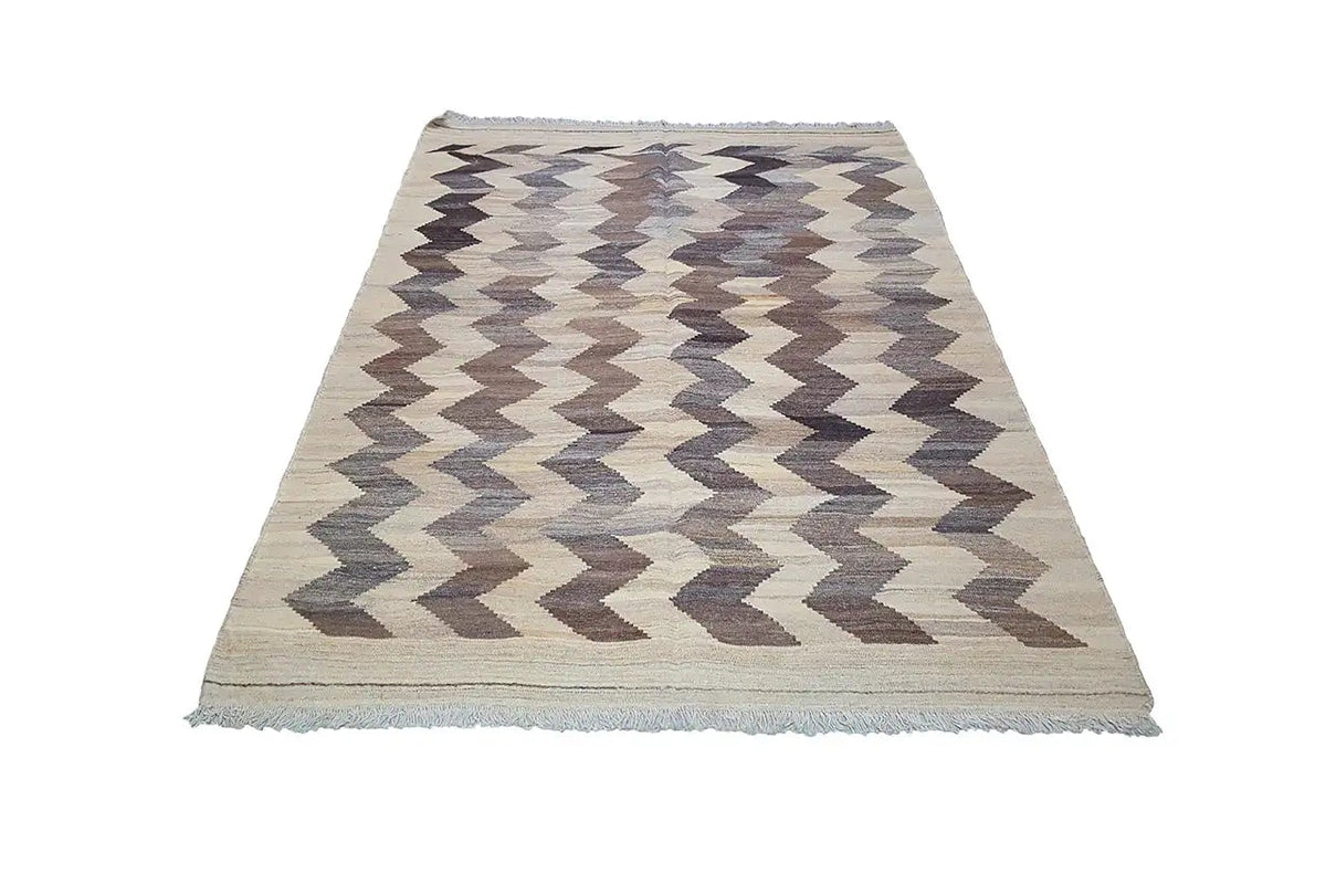 Kilim rug with zigzag chevron pattern, light beige background, gray-brown, with fringes.