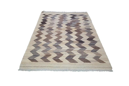Kilim rug with zigzag chevron pattern, light beige background, gray-brown, with fringes.
