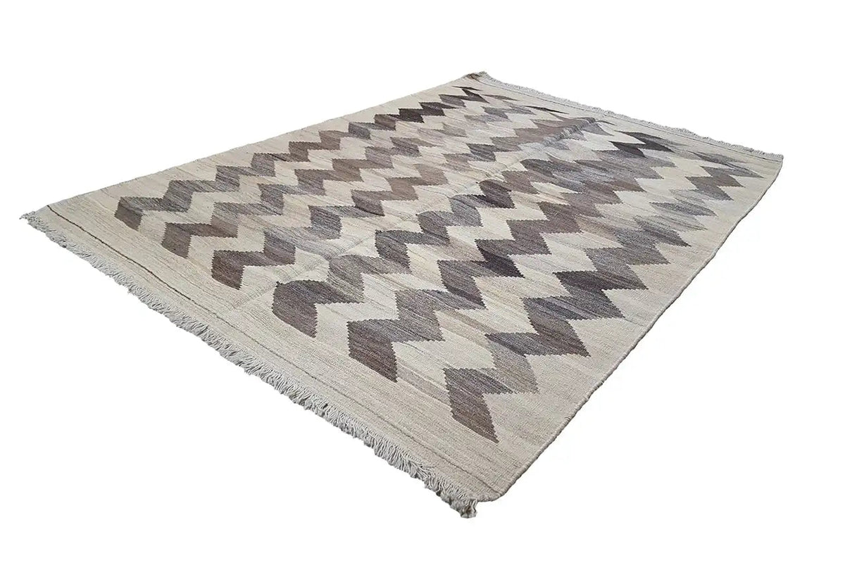 Kilim rug with a geometric zigzag pattern, light beige and gray-brown, fringed edges.