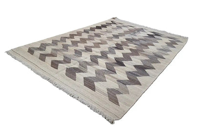 Kilim rug with a geometric zigzag pattern, light beige and gray-brown, fringed edges.