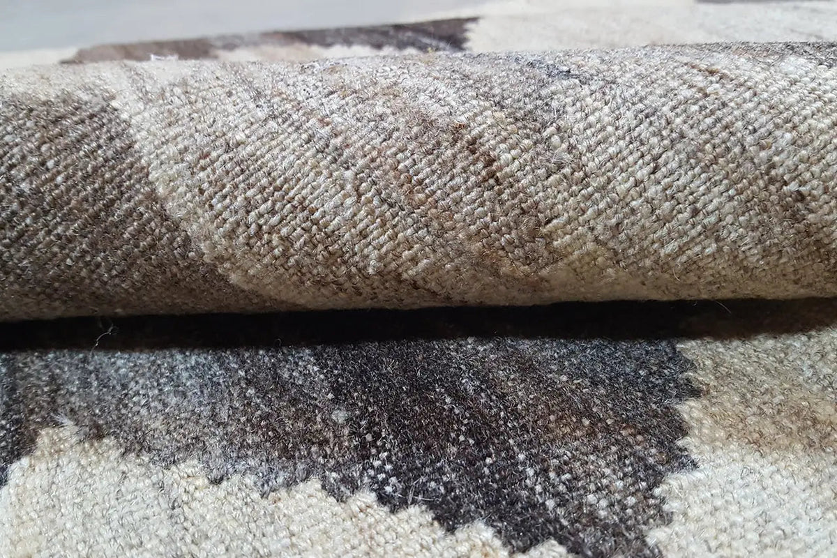 Kilim rug close-up: woven texture, light beige fibers, gray-brown zigzag.