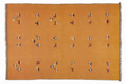 Rectangular ochre-brown kilim rug with delicate multicolored patterns and a fringed edge
