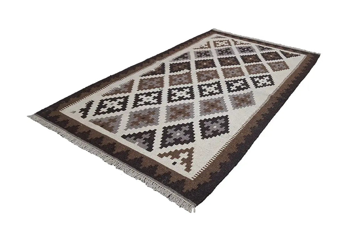 Kilim rug, lying at an angle, with diamond and zigzag patterns in brown and beige
