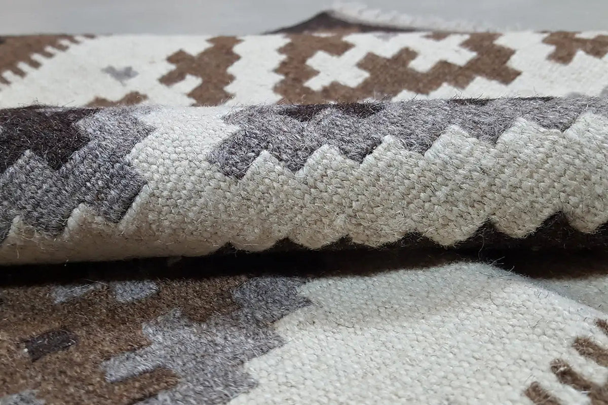 Close-up: kilim with a flat pile and woven patterns in beige and gray