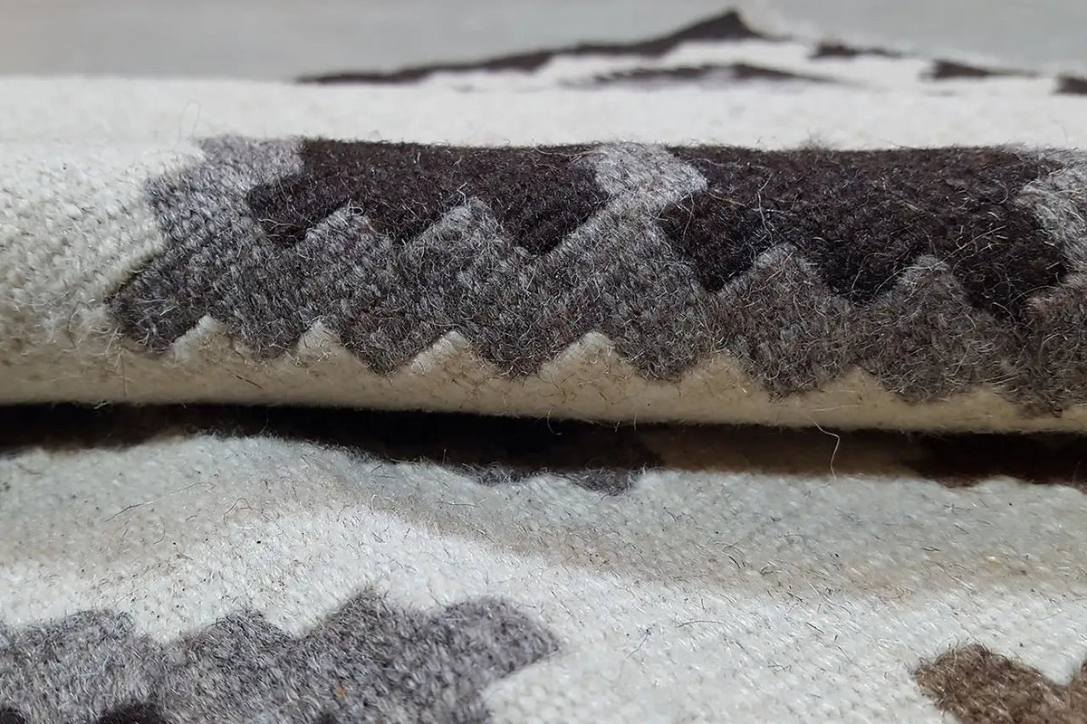 Kilim rug with fringed edges, patterned in gray, black, and cream