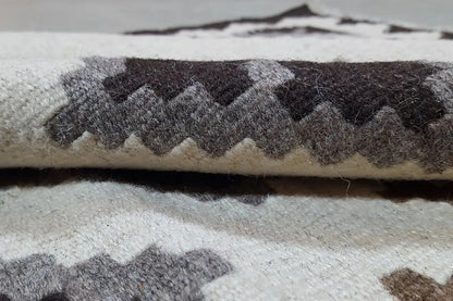 Kilim rug with fringed edges, patterned in gray, black, and cream