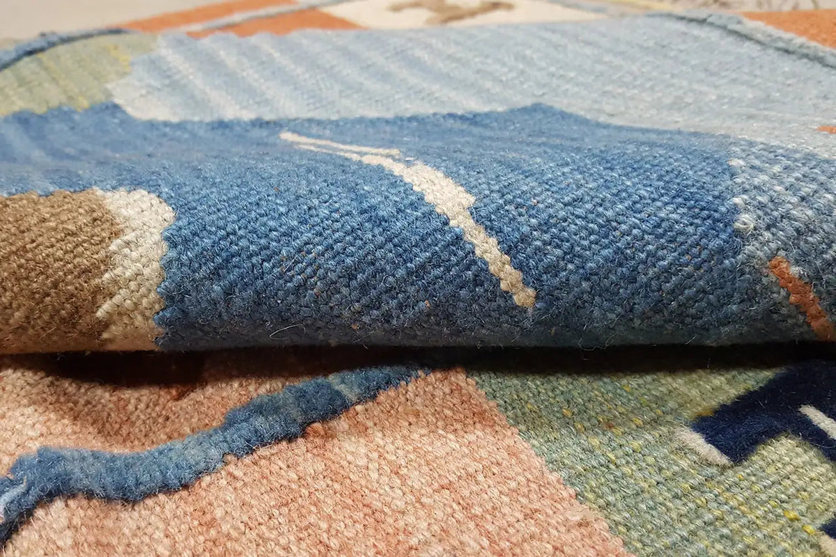 Kilim rug close-up: blue and beige weave with colorful accents and piles of pile fibers