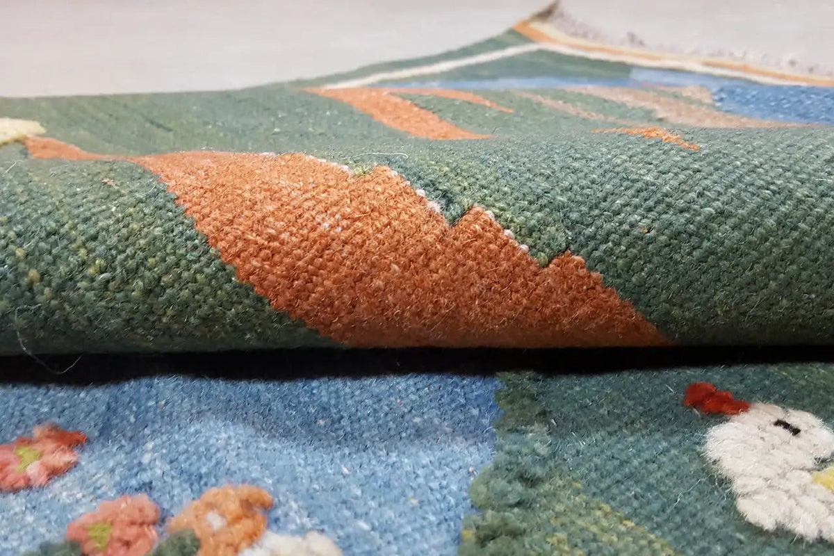Close-up: green-orange kilim surface with a woven texture and fringed edge