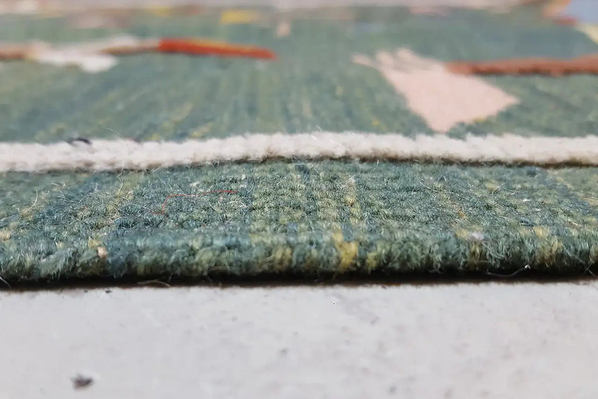 Close-up of the kilim rug edge: woven border with fringe and green pile area