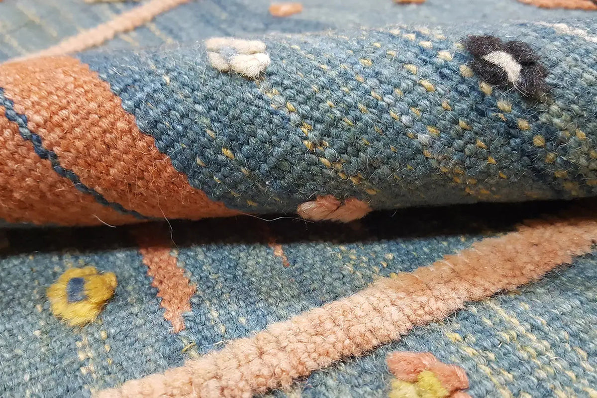 Close-up: blue wool fabric with beige decorative stripes and colorful woven motifs