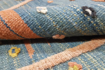 Close-up: blue wool fabric with beige decorative stripes and colorful woven motifs