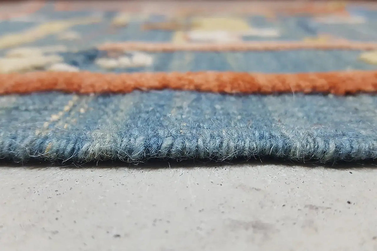 Kilim border with short fringes; blue patterned fabric on a beige background
