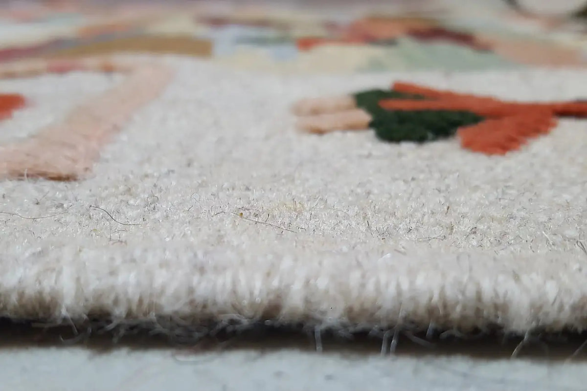 Close-up of carpet edge: dense pile with light-colored fibers and short fringes