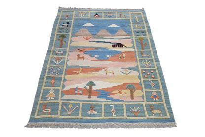 Kilim rug with a blue field, multicolored landscape motifs, and fringes along the edge