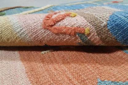Close-up of the kilim rug: colorful woven texture with short pile and edge fringes