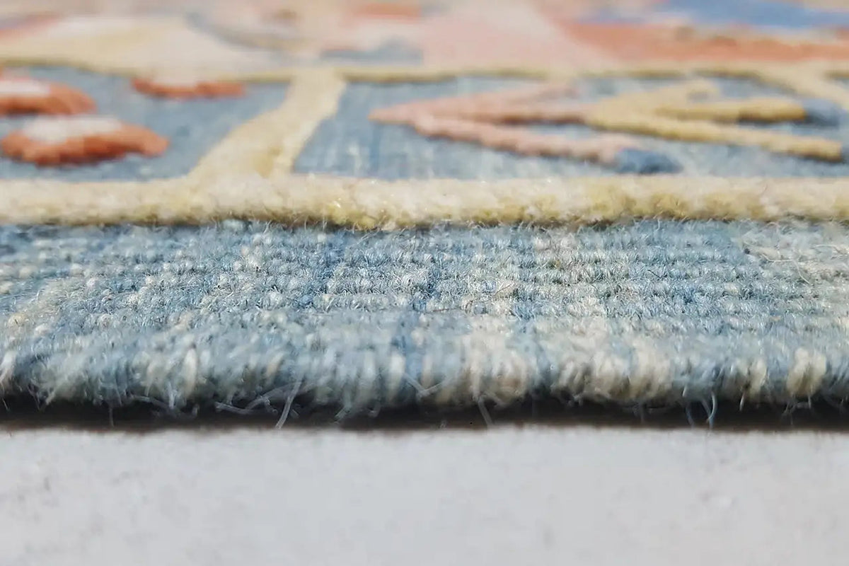 Close-up of the carpet edge: blue woven pattern with a frayed finish