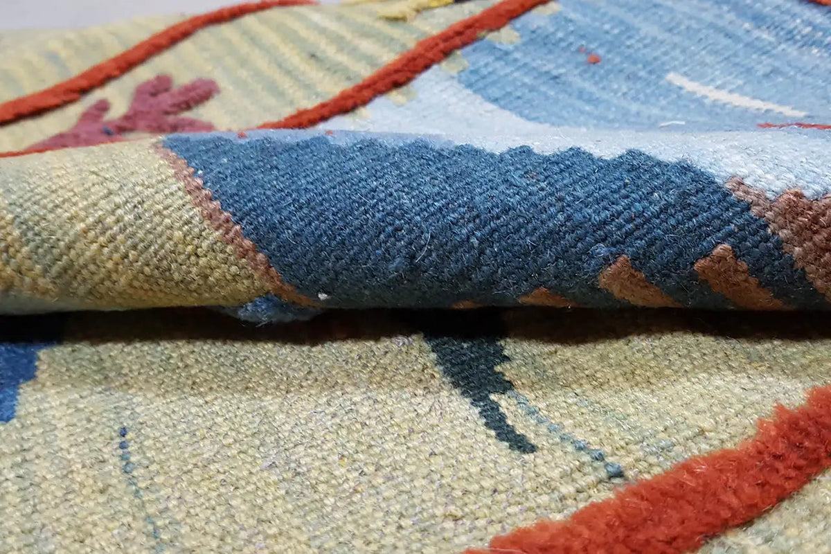 Detail of the kilim rug: woven pile with a blue field, red border, and fringes