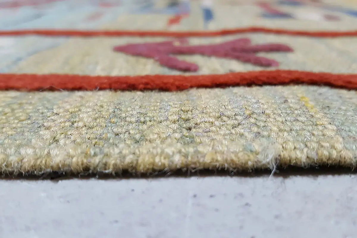 Close-up of the carpet edge with a short pile, beige background, and red decorative line