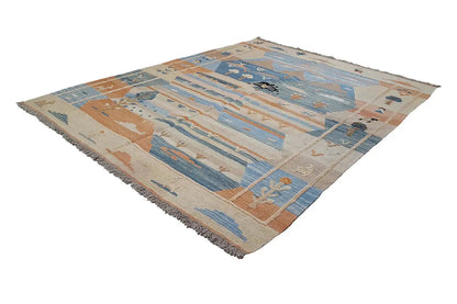 Kilim rug with a diamond pattern, blue and beige with brown-orange accents, fringes along the edges.