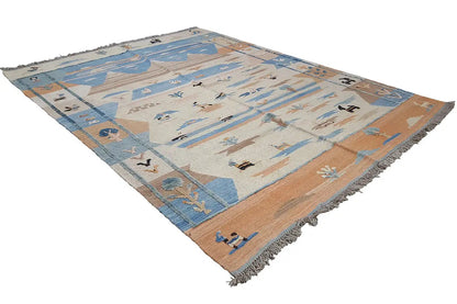 Rectangular kilim rug, shown at an angle: blue and beige pattern with fringes