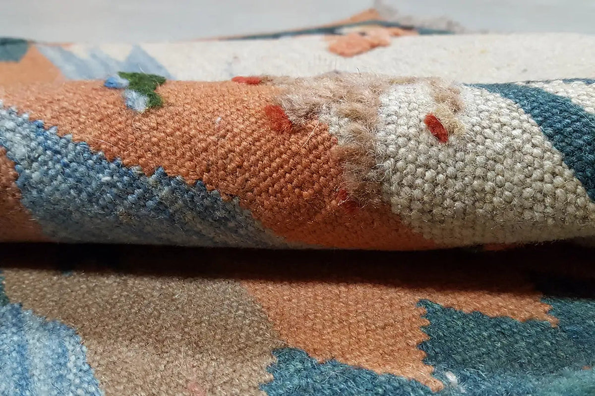 Close-up of the kilim rug: multicolored woven texture and fringe along the edges