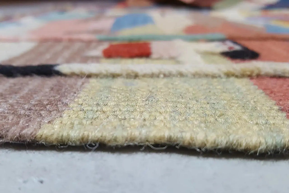 Detail of the carpet edge: pile and weave structure with multicolored patterns, slightly aged