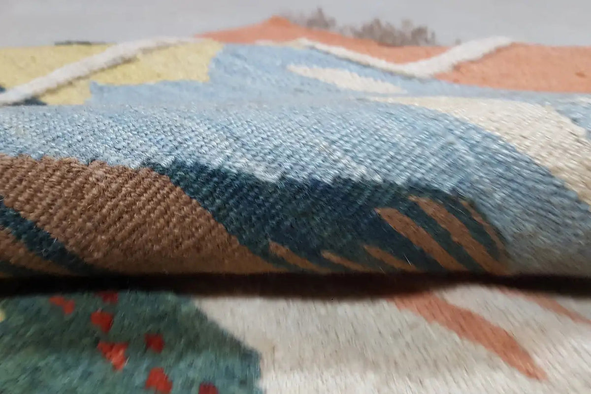 Close-up of a kilim rug: woven surface with a blue-brown pattern and embossed texture