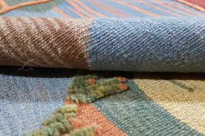 Woven kilim with blue-gray pile and colorful flecks, visible weave texture