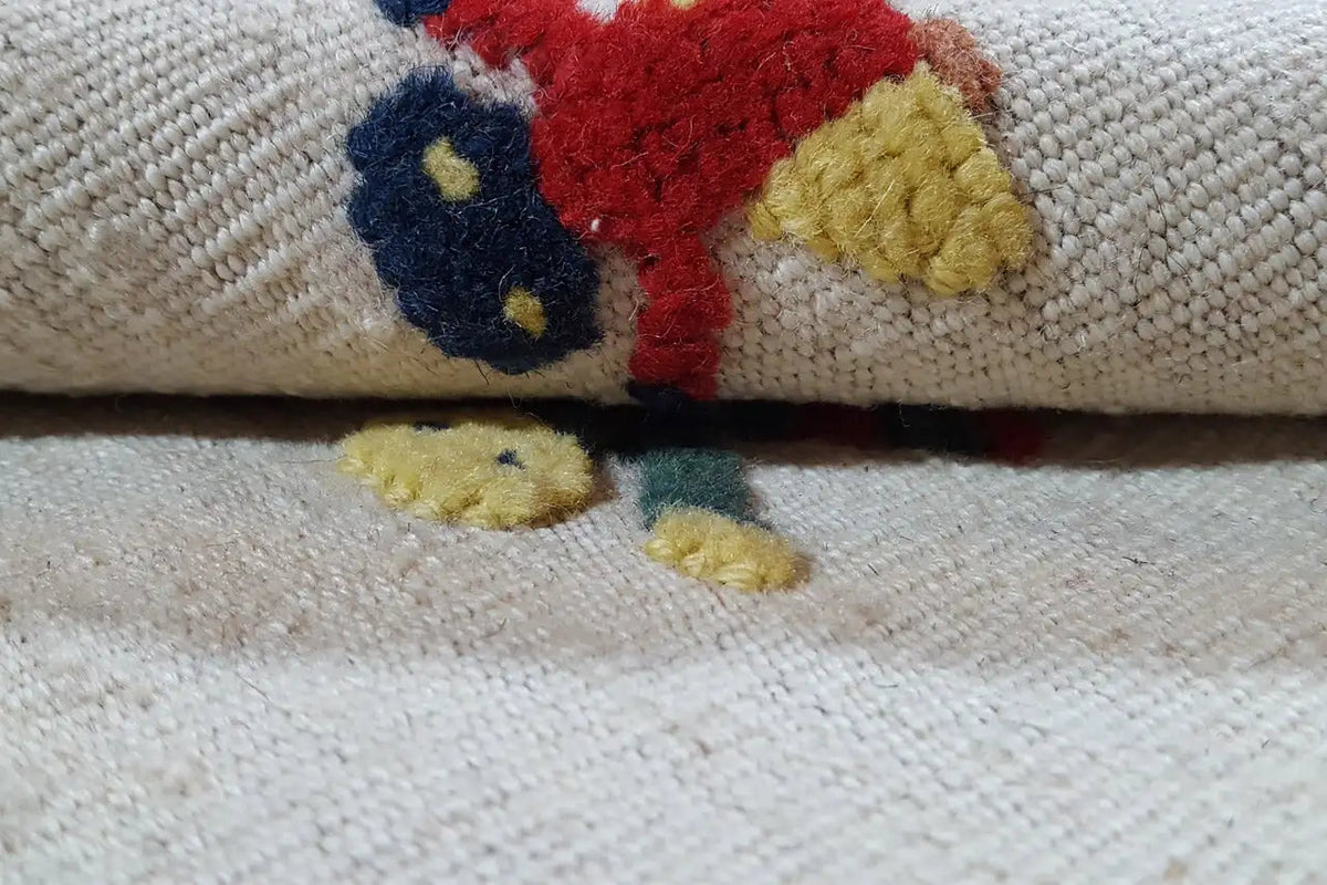 Kilim rug detail: short-pile weave with red, blue, and yellow motifs along the edge