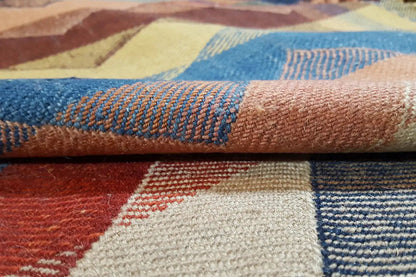 Close-up: rug edge with a woven texture and zigzag pattern in blue, cream, and red.
