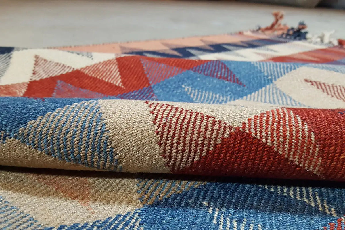 Rug detail: woven surface with zigzag and color stripes in blue, red, and beige