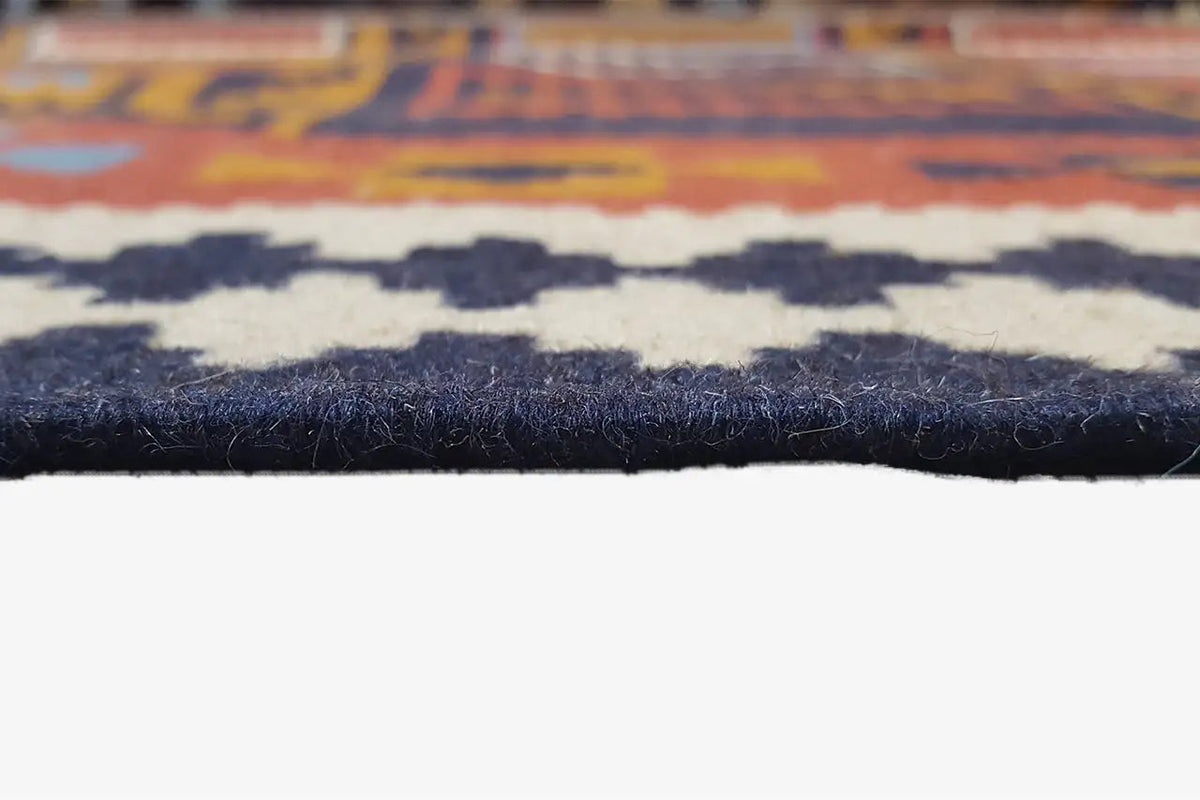 Kilim rug edge with fringe; dark border and multicolored patterns