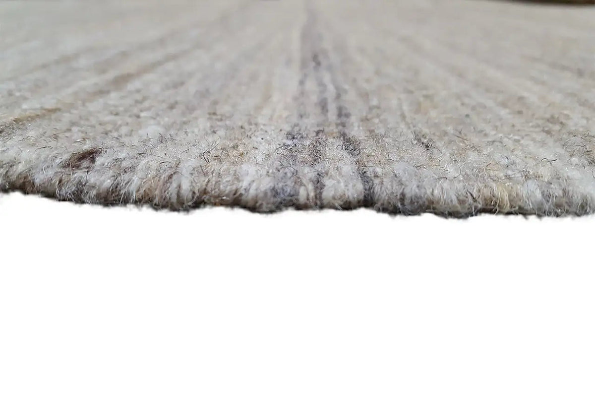 Kilim rug edge close-up, light beige-gray mottled fabric, selvedges visible