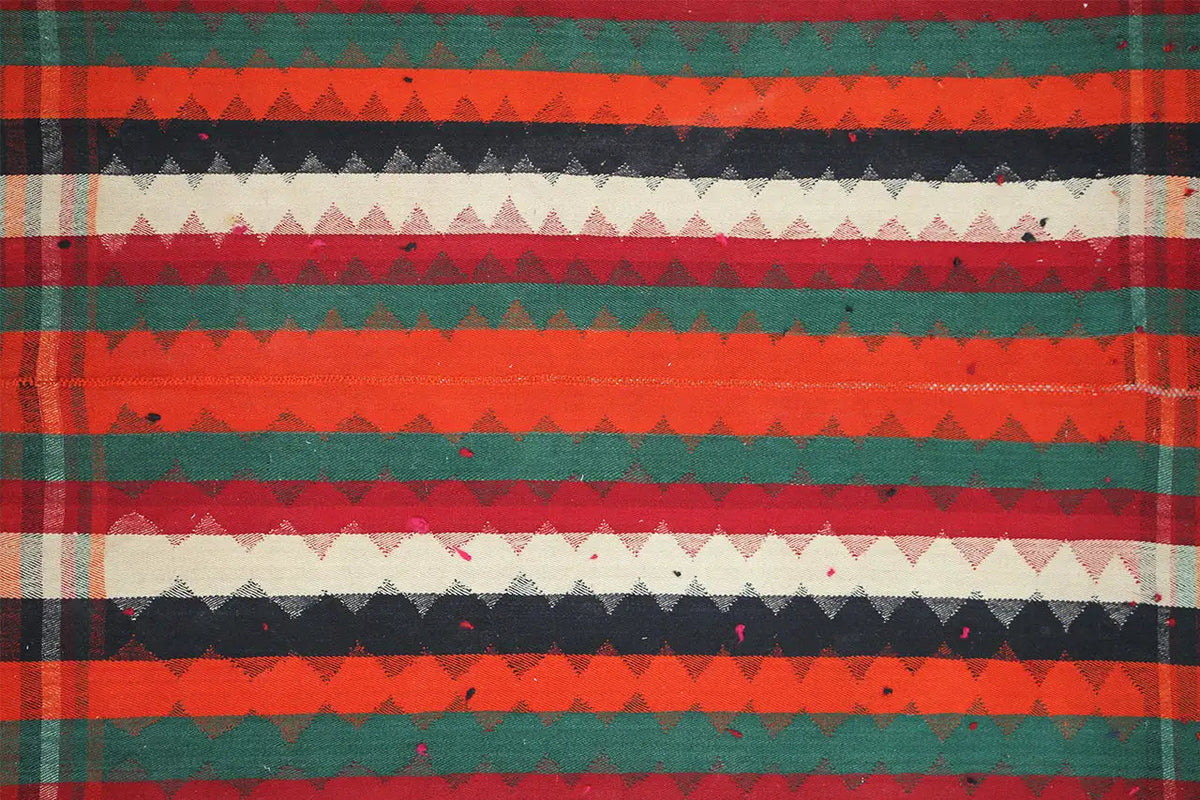 Close-up of a jajim rug: horizontal stripes in red, green, dark blue, and cream.